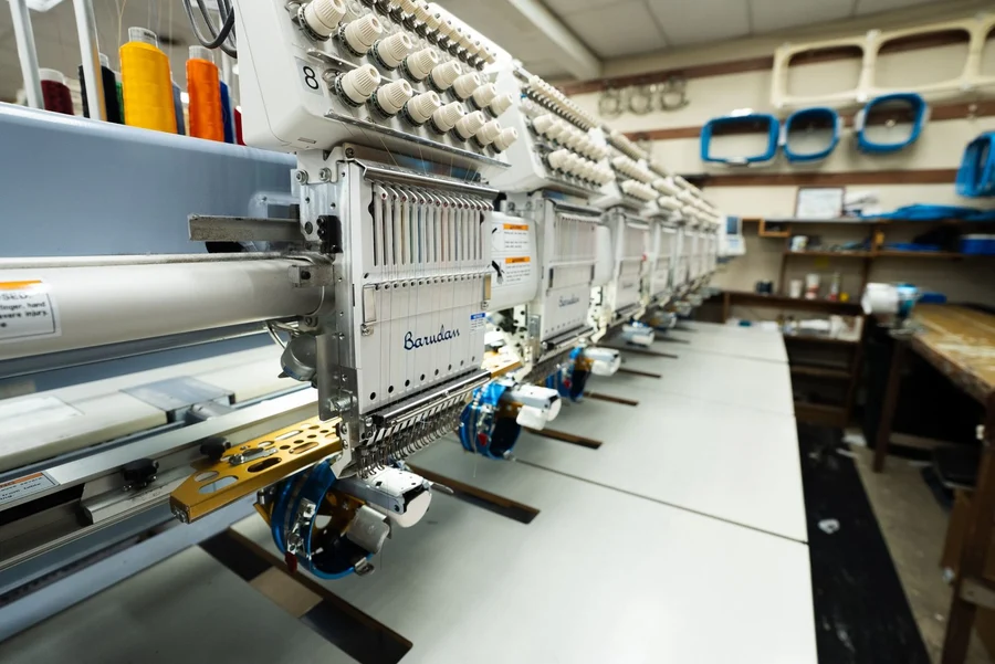 A row of embroidery machines with colorful thread